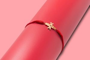 photo of a JUN by Eliza Kuo bracelet: a gold cross at the center with red silk string